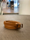 A 0.75 inch wide belt in camel vegan leather, nickel-free brass buckle.