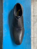 A black vegan leather men's dress shoe with subtle perforated detailing. Lace up closure with 5 eyelets. Slightly tapered squared toe.